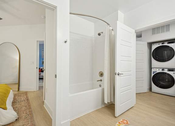 a bathroom with a washer and dryer and a door to a laundry room at Link Apartments® Calyx, Chapel Hill