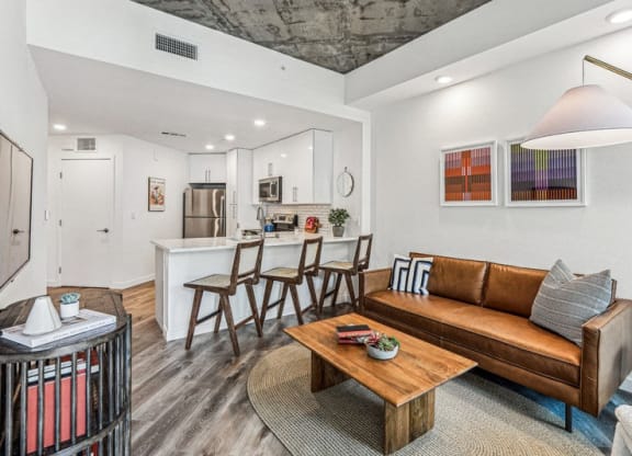 a living room with a couch and a coffee table in front of a kitchen at Link Apartments® Four 12, Oakland