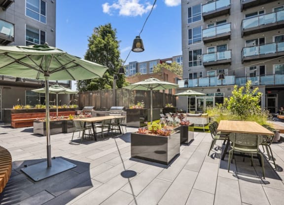 a patio with tables and chairs and umbrellas at Link Apartments® Four 12, Oakland, 94607
