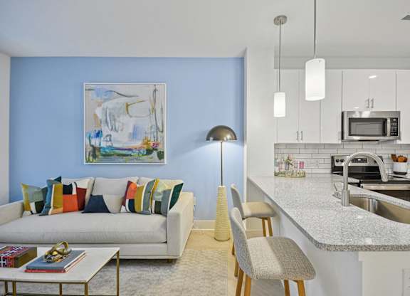 a living room with a couch and a kitchen at Link Apartments® Calyx, Chapel Hill, NC