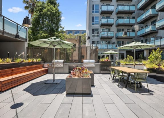 a rendering of a patio with tables and umbrellas at Link Apartments® Four 12, Oakland