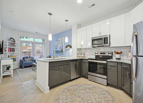 a kitchen with stainless steel appliances and white cabinets at Link Apartments® Calyx, Chapel Hill