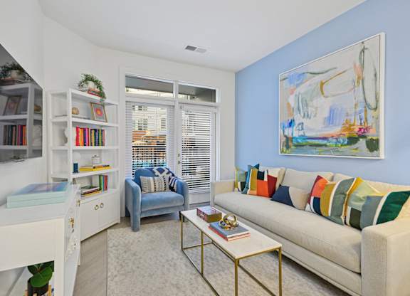 a living room with a couch and a chair and a window at Link Apartments® Calyx, Chapel Hill