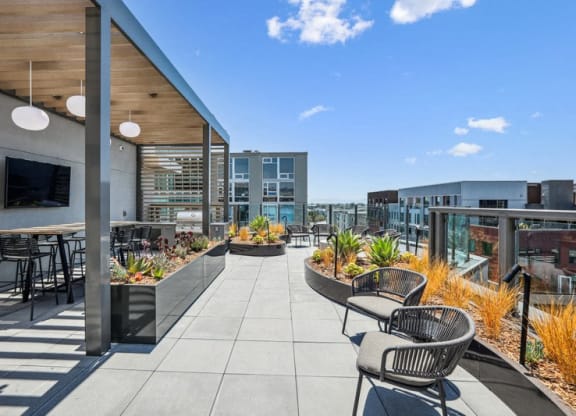 the settlement rooftop patio with tables and chairs and a tv at Link Apartments® Four 12, Oakland, CA