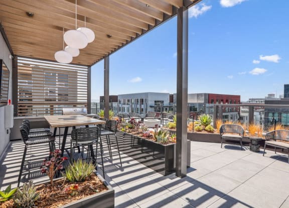 a patio with tables and chairs on the roof of a building at Link Apartments® Four 12, California, 94607