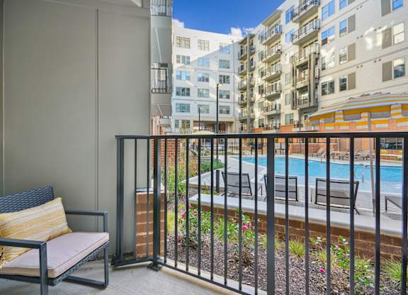 the view of a pool from a balcony with a chair at Link Apartments® Calyx, Chapel Hill
