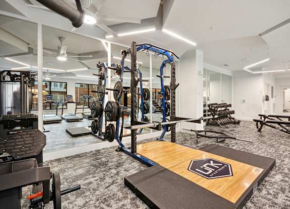 a gym with weights and cardio equipment in a building with white walls at Link Apartments® Calyx, Chapel Hill, 27517