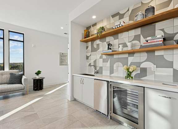 a kitchen with white cabinets and a large window at Link Apartments® Calyx, Chapel Hill, NC 27517