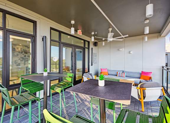 a patio with tables and chairs and sliding glass doors at Link Apartments® Calyx, Chapel Hill, NC 27517