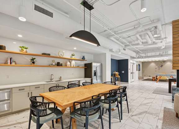 a dining room with a wooden table and black chairs at Link Apartments® Calyx, Chapel Hill