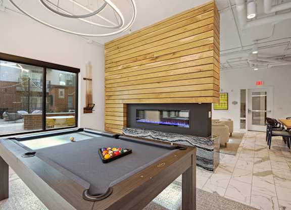 clubhouse with pool table and fireplace at the district at highland village apartments at Link Apartments® Calyx, North Carolina, 27517