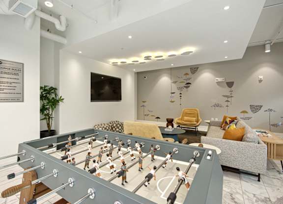 a game room with a foosball table and a couch at Link Apartments® Calyx, Chapel Hill, NC