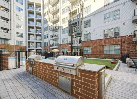 a barbecue grill on a brick wall in front of an apartment building at Link Apartments® Calyx, North Carolina, 27517
