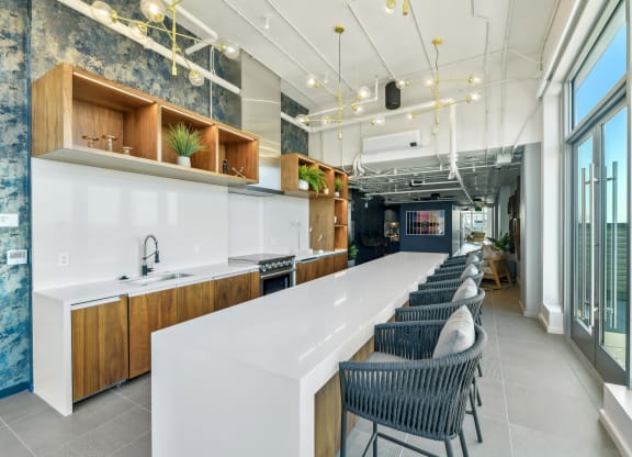 a long kitchen with a long white counter and chairs  at Link Apartments® H Street, Washington, 20002