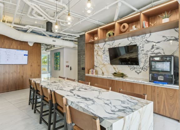 a long marble table with chairs in a room with a tv at Link Apartments® H Street, Washington, 20002