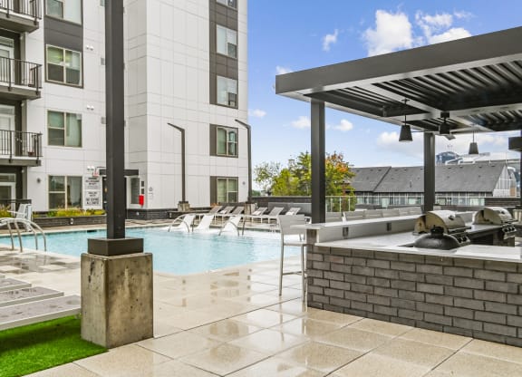the estates at tanglewoodpool with spa and grilling area with buildings at Link Apartments® Mint Street, North Carolina