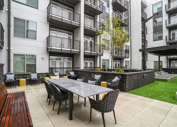 an outdoor patio with a table and chairs in front of an apartment building at Link Apartments® Mint Street, Charlotte, NC, 28203