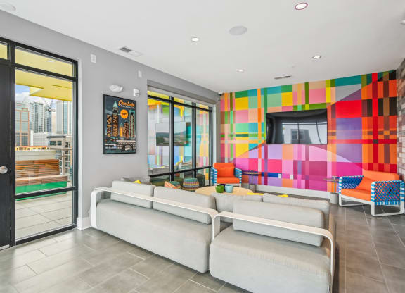 a living room with couches and a television and a colorful wall at Link Apartments® Mint Street, North Carolina