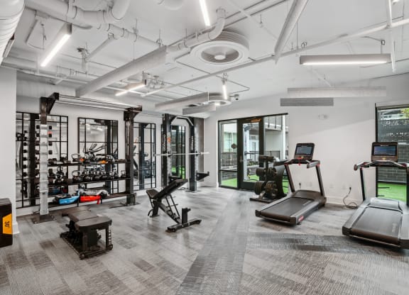 a workout room with treadmills and other equipment in a building with white walls at Link Apartments® Mint Street, Charlotte, NC