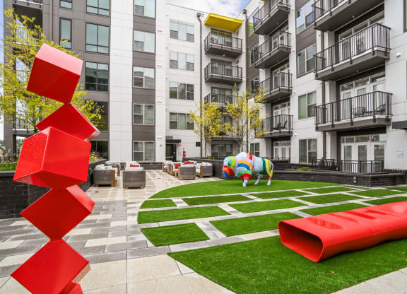 an apartment courtyard with a large red sculpture in front of an apartment building at Link Apartments® Mint Street, Charlotte, North Carolina