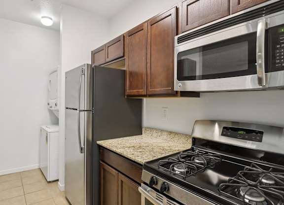 A kitchen with a black refrigerator, stove, and microwave. at Rome Park Villas, North Las Vegas, Nevada