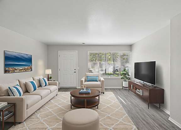 A living room with a couch, chair, ottoman, and television.