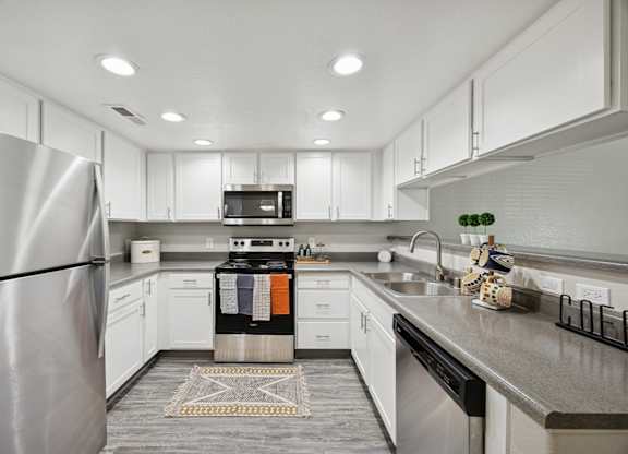 A modern kitchen with a stainless steel refrigerator and white cabinets.
