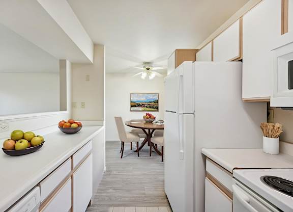 A kitchen with white appliances and a table with chairs.