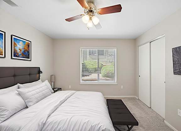 A bedroom with a large bed and a ceiling fan.