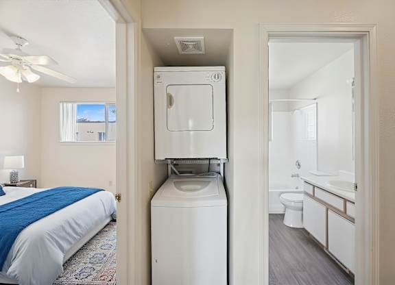 A bedroom with a bed, a washing machine, and a bathroom.