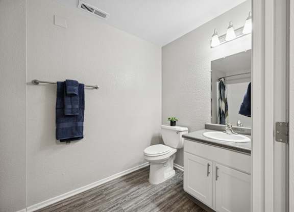 A bathroom with a toilet, sink, and a mirror.