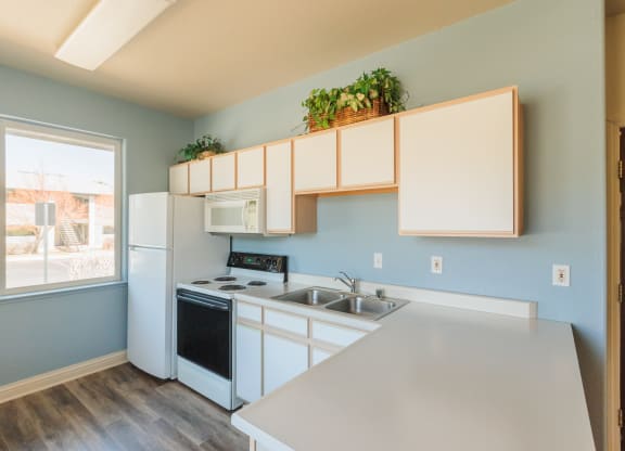 an empty kitchen with white appliances and a large window