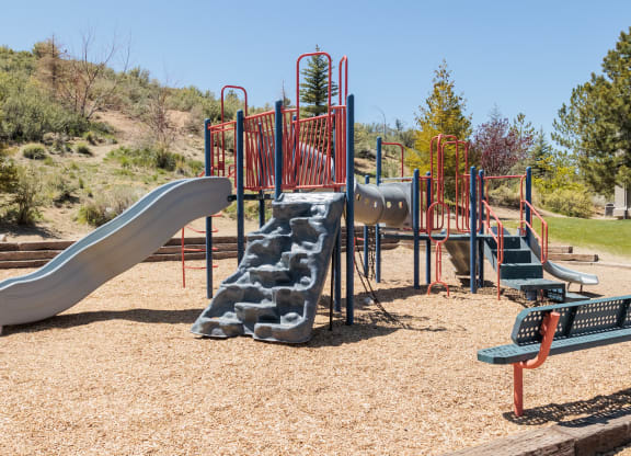 a playground with slides and benches in a park