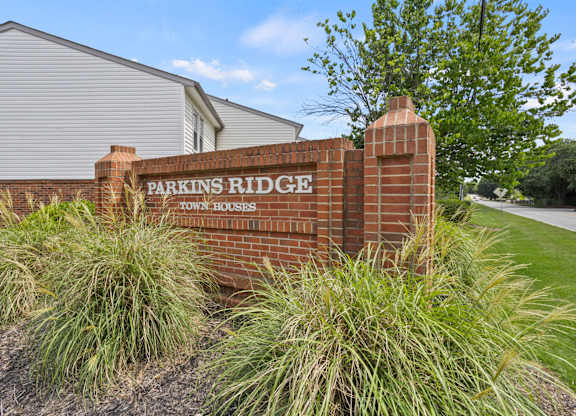 A brick sign that says Parkins Ridge in front of a building.
