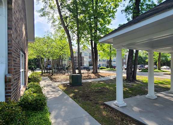 a sidewalk in front of a building with trees