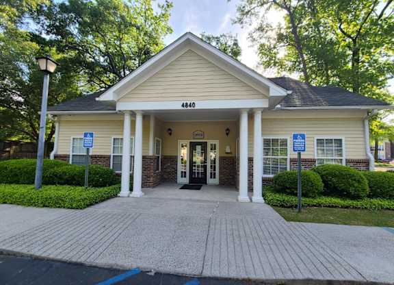 the front entrance of a cream colored building with pillars and a porch