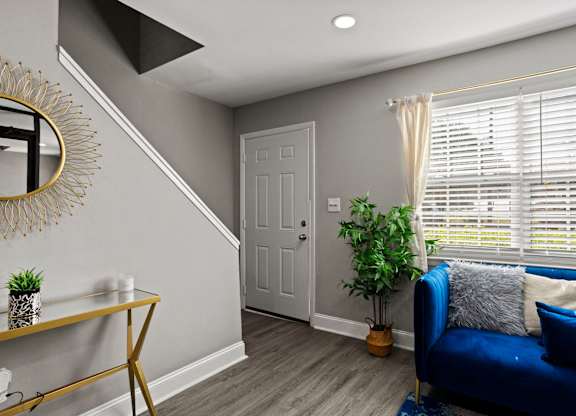 A blue couch sits in front of a window with white blinds.
