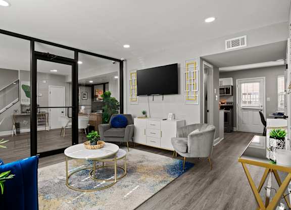 A modern living room with a glass table and a TV on the wall.