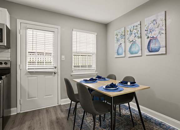 A dining room with a table set for two and two vases on the wall.