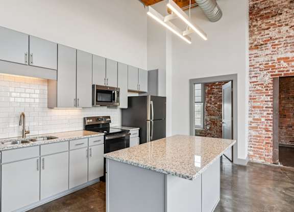 Kitchen in Converse Mill Lofts in Spartanburg, SC with granite countertops, gray cabinetry and stainless steel appliances