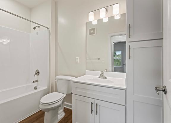 A white bathroom with a toilet, sink, and mirror.