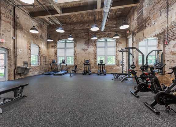 Newry Mill private 24 hour gym. Included are bench chairs, stationary bikes, treadmills, ellipticals, a mirror, assisted bench press station, and a water bottle refill station.