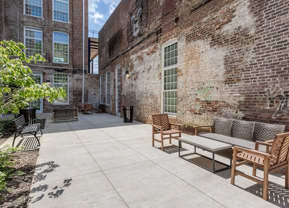 Newry Mill outdoor community patio. Outdoor couches, benches and chairs are pictured along with trashcans.
