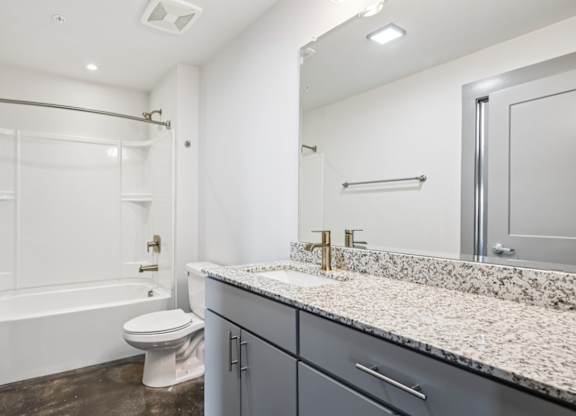 Bathroom in Converse Mill Lofts in Spartanburg, SC with granite countertops and tub/shower