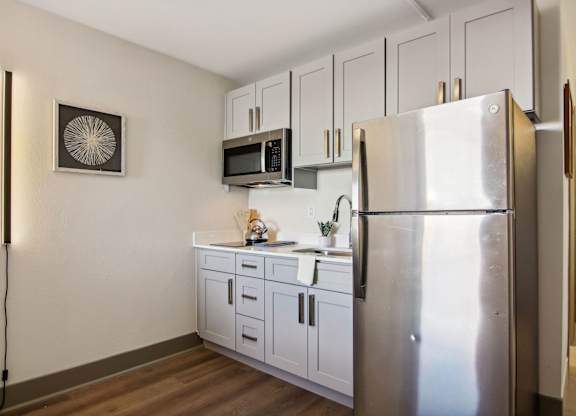 Greenville, SC Apartments | Flathouse Studios | Kitchen with Stainless-Steel Appliances, Quartz Countertops, Integrated Cooktop, and White Cabinetry.