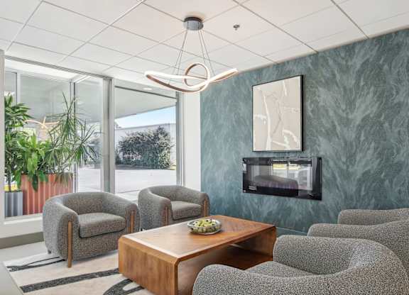 a living room with chairs and a table and a fireplace