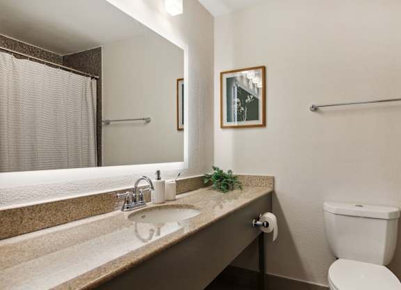 Furnished Studio Apartments | Flathouse Studios | Bathroom with Quartz Countertop, Undermount Sink, and Large Backlit Mirror.