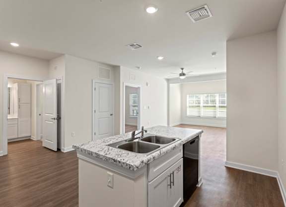 Peaks of Lexington Apartments Kitchen with Black Appliances, Granite Countertops and White Cabinetry and connected living room