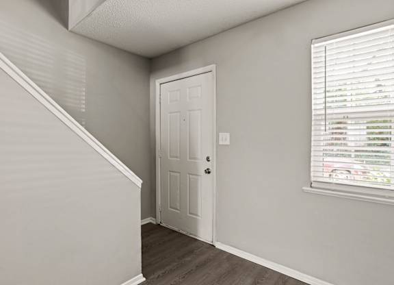 A white door is in a room with a window.