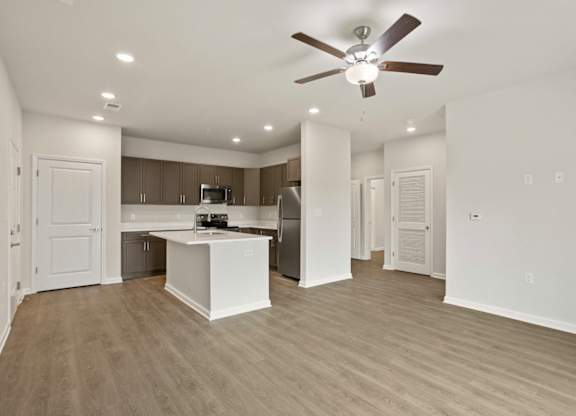 A spacious kitchen and living room with a ceiling fan.